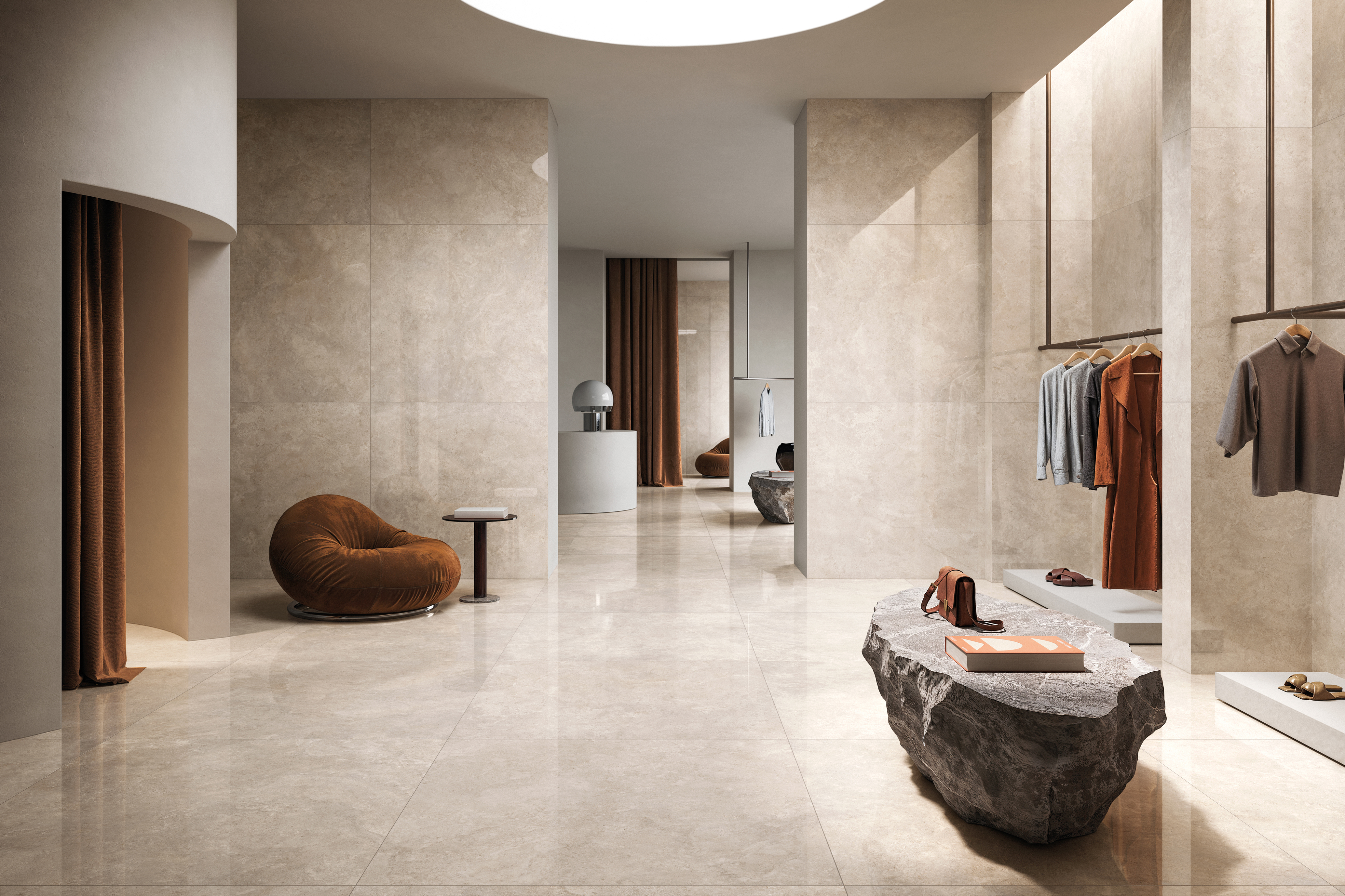 High-end retail setting with greige tile walls and floors, rough stone tables and plush brown chairs