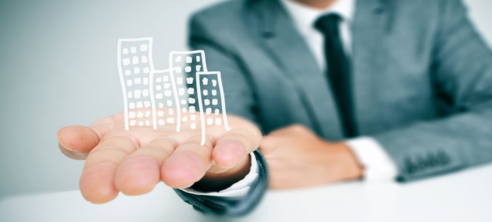 Man in suit holding graphic of buildings