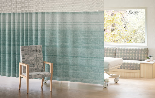 Healthcare setting with chair, curtain, then rolling bed and sofa