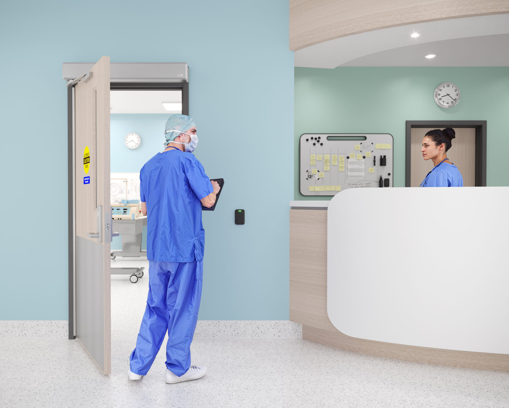 Man in blue scrubs by open door and woman in scrubs behind counter, in healthcare setting