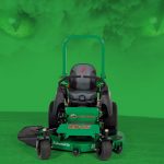 Aggressive-looking black-and-green riding mower with green eyes and cloud above