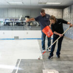 Two workers applying Bona Commercial System Concrete Floor Solution