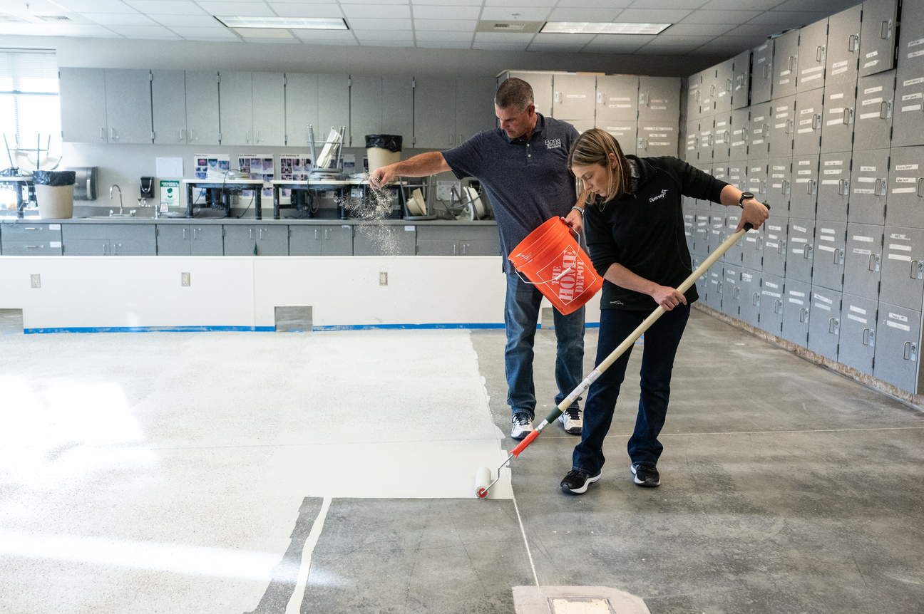 Two workers applying Bona Commercial System Concrete Floor Solution 