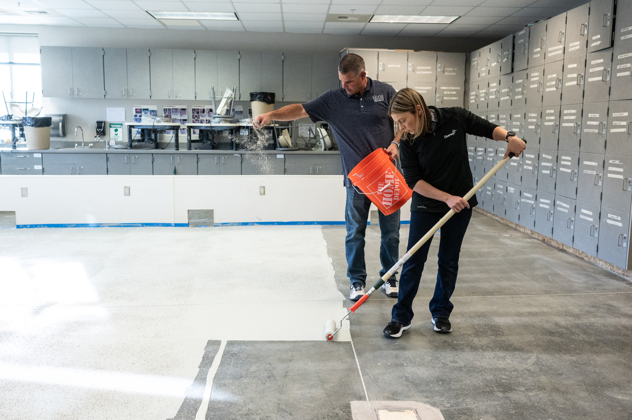 Two workers applying Bona Commercial System Concrete Floor Solution