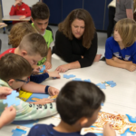 Teacher and children at table, illustrating KI’s Classroom Furniture Giveaway