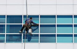A man cleaning Architecturally Finished Aluminum on windows on a high rise building